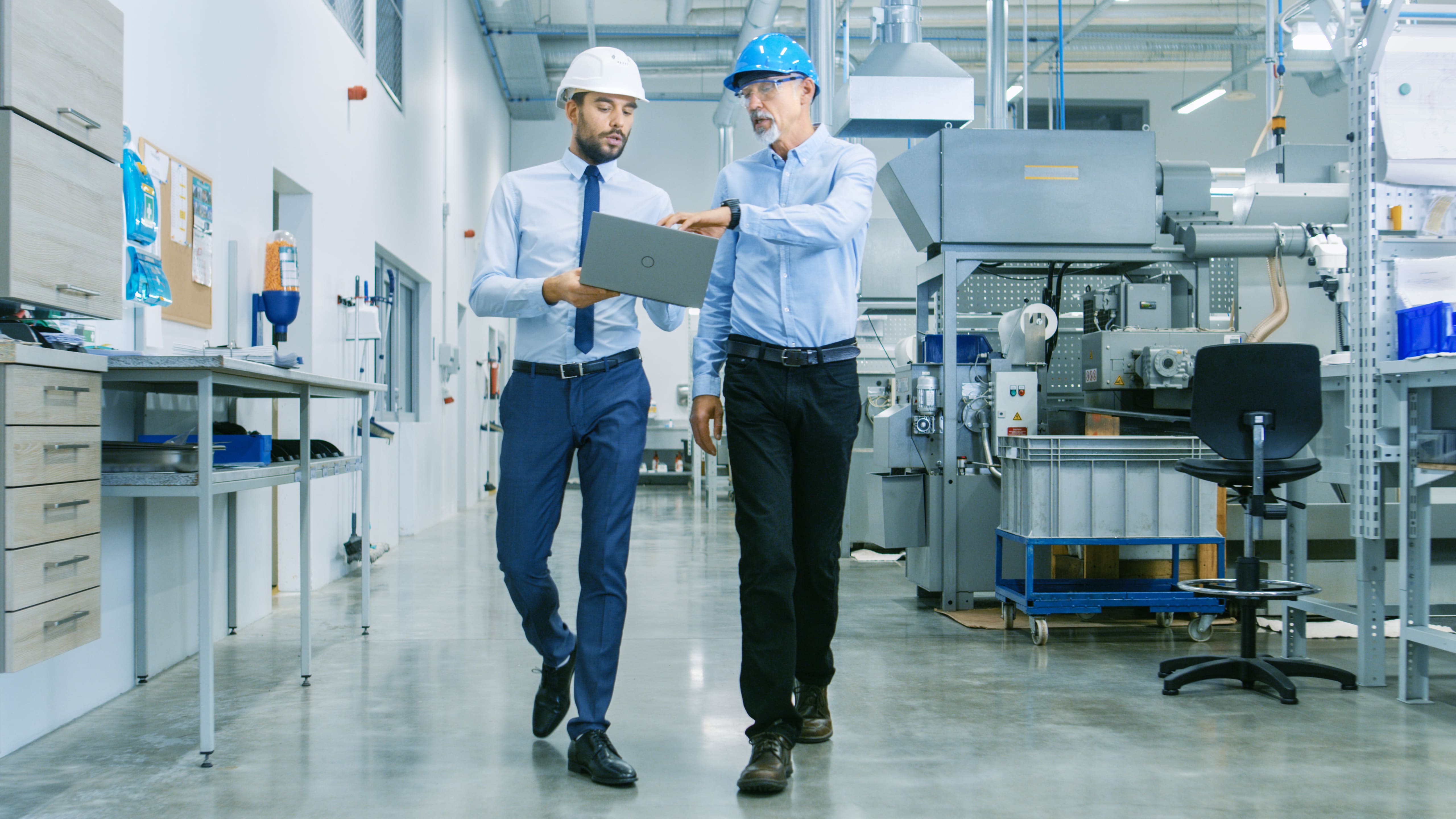 Two men with computer walking in warehouse