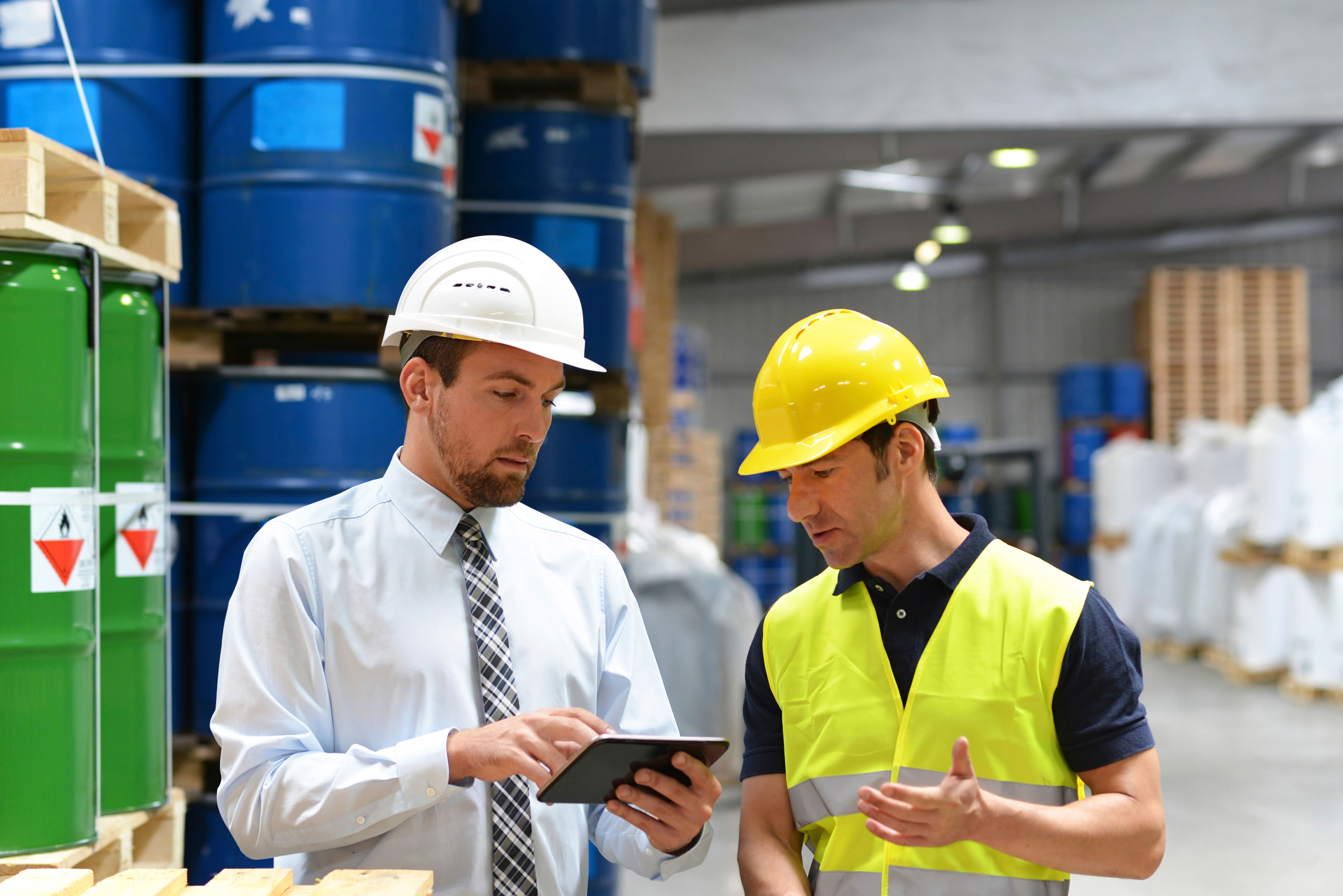 Two workers looking at tablet in a chemical storage facility