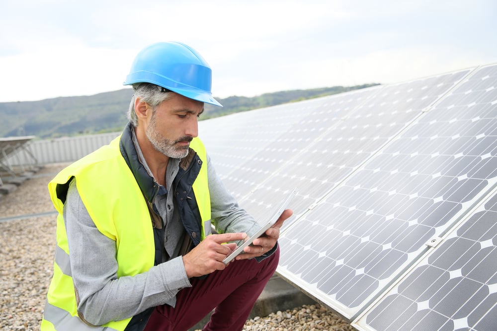 Mature engineer on building roof checking solar panels-1